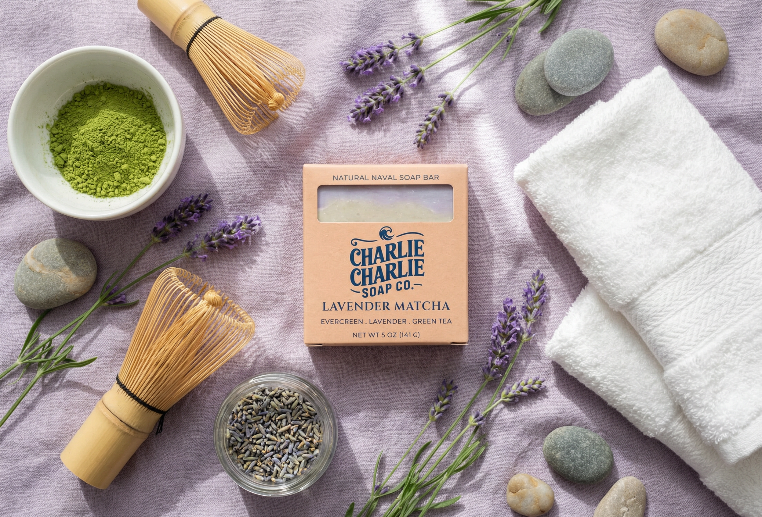 Lavender Matcha soap bar from Charlie Charlie Soap Co. with matcha powder, lavender flowers, and stones on a textured surface.