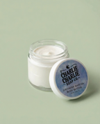 Jar of body butter with a blue label on a light green background
