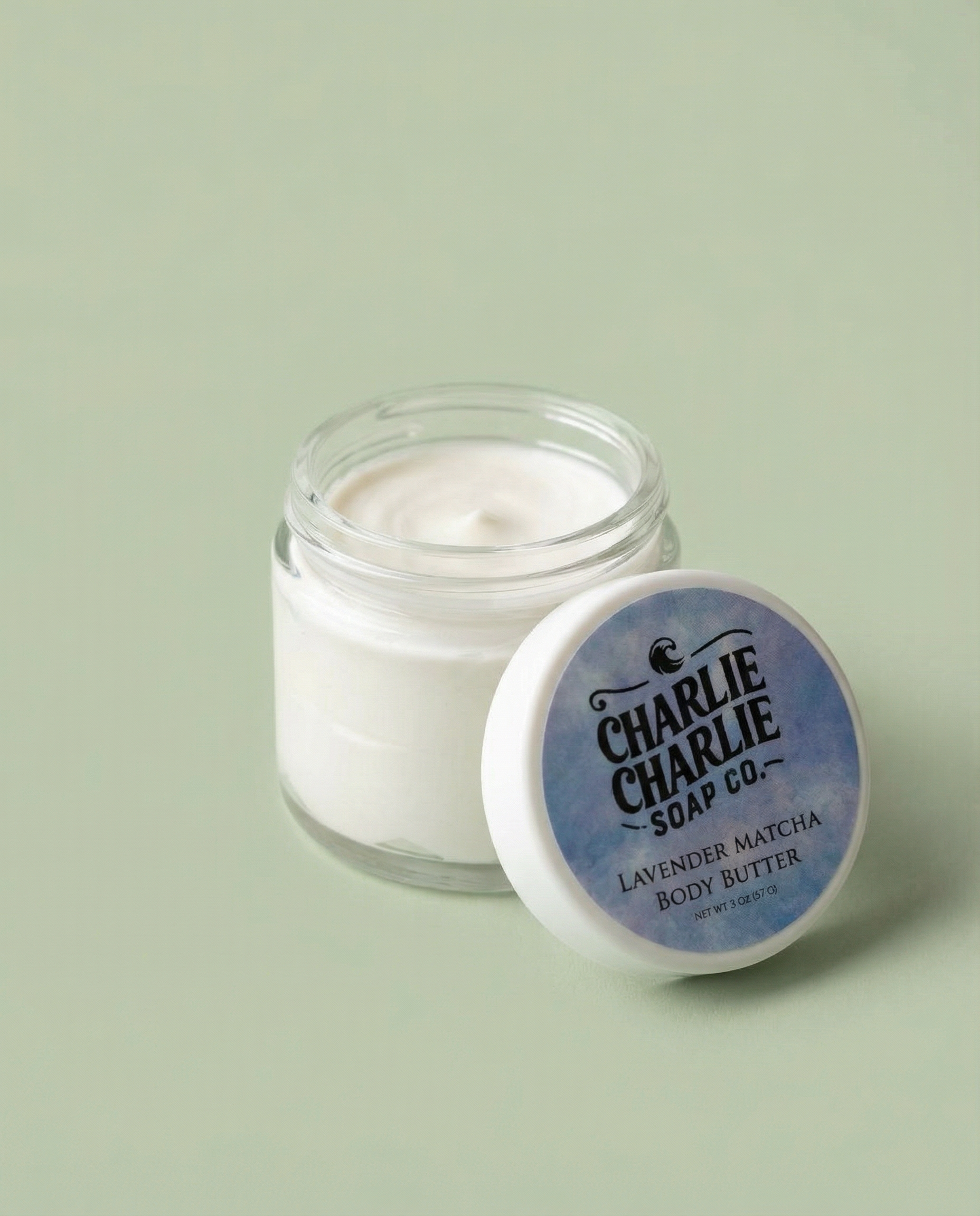 Jar of body butter with a blue label on a light green background