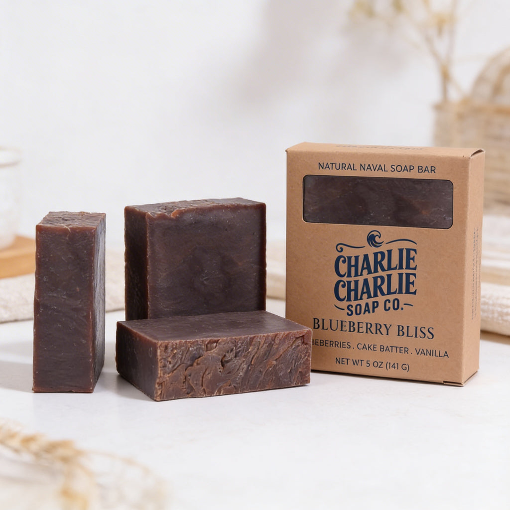 Three bars of soap and a cardboard box from Charlie Charlie Soap Co. on a white surface.