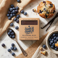 Charlie Charlie Soap Co. Blueberry Bliss soap bar with blueberries, a muffin, and vanilla beans on a marble surface.
