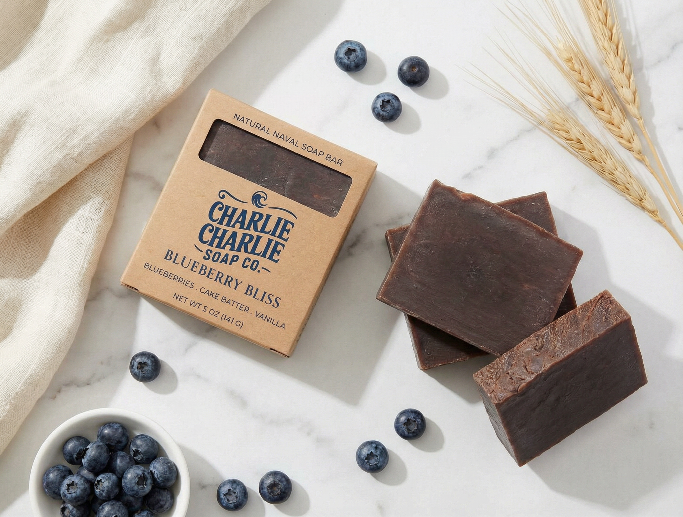 Chocolate soap bars with packaging and blueberries on a marble surface