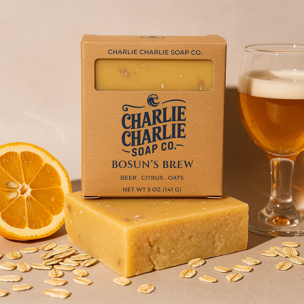 Bar of Charlie Charlie Soap Co. soap with packaging, an orange, and a glass of beer on a beige background.