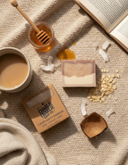 Bar of soap with packaging, honey, and a book on a textured surface