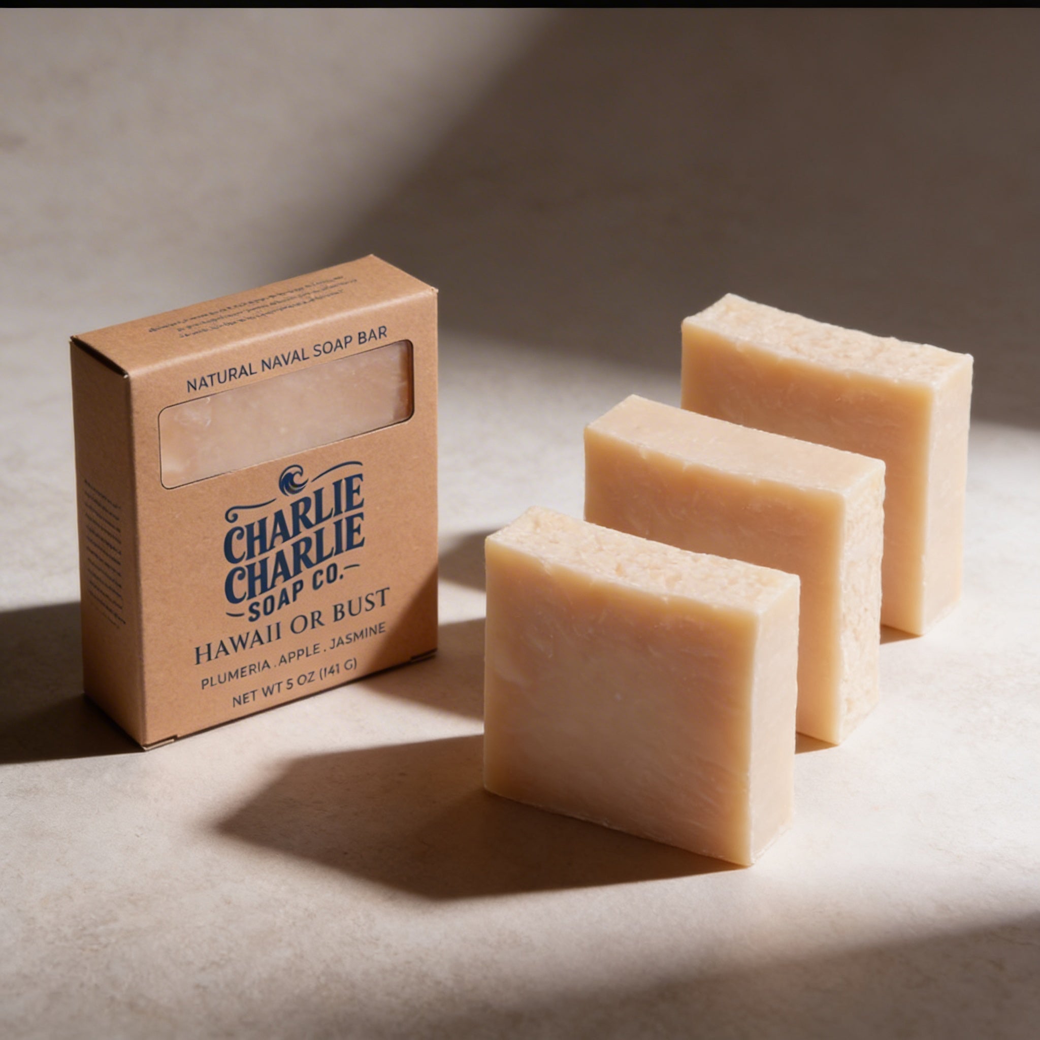 Three bars of soap and a box from Charlie Charlie Soap Co on a neutral background
