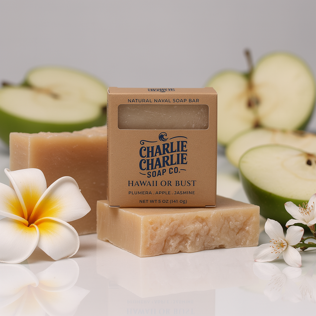 Two bars of soap with a box labeled 'Charlie Charlie Soap Co.' surrounded by halved apples and flowers on a light background.