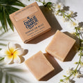 Two bars of soap and their packaging with floral elements on a light background