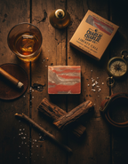 Bar of soap with a wooden background featuring a glass of whiskey, a cigar, and a compass.