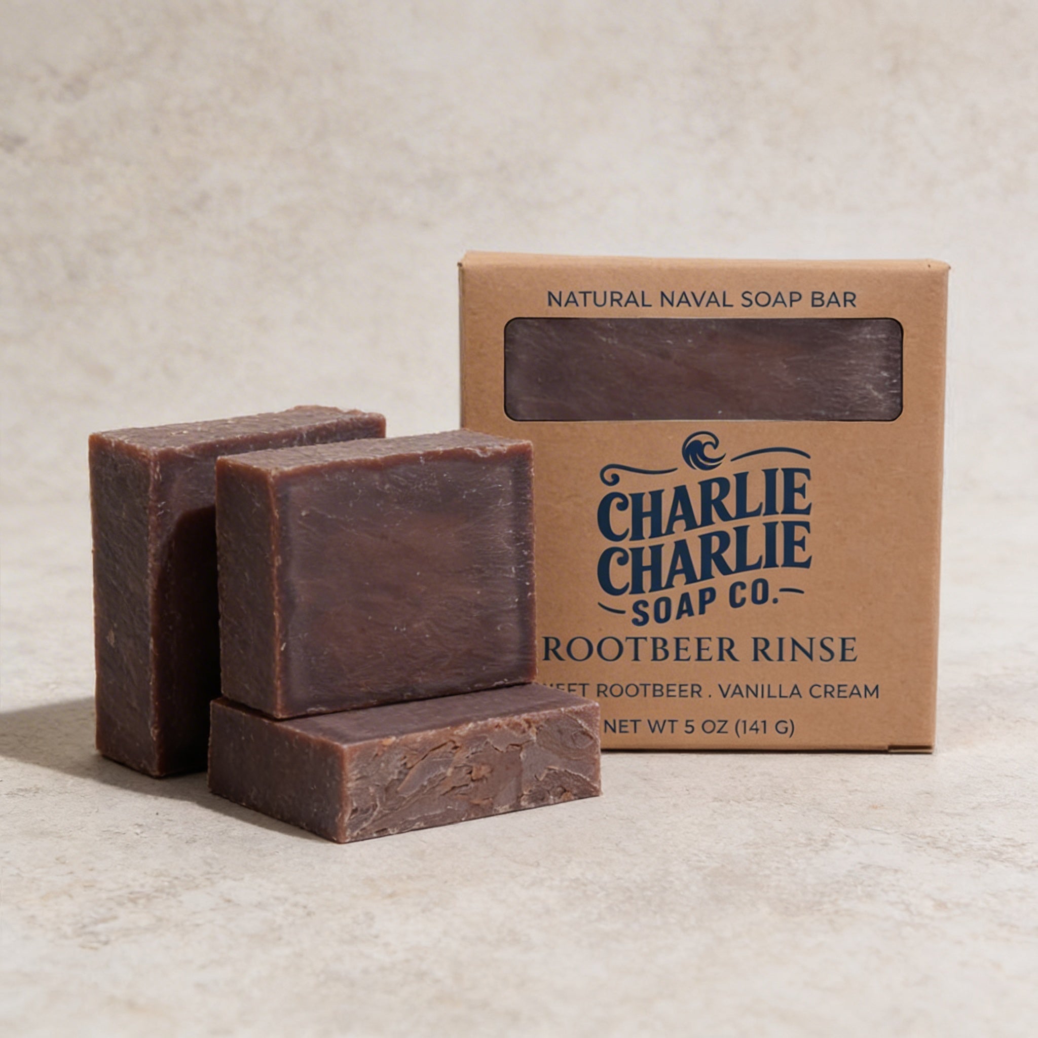 Three bars of Charlie Charlie Soap Co. soap with a packaging box on a beige background
